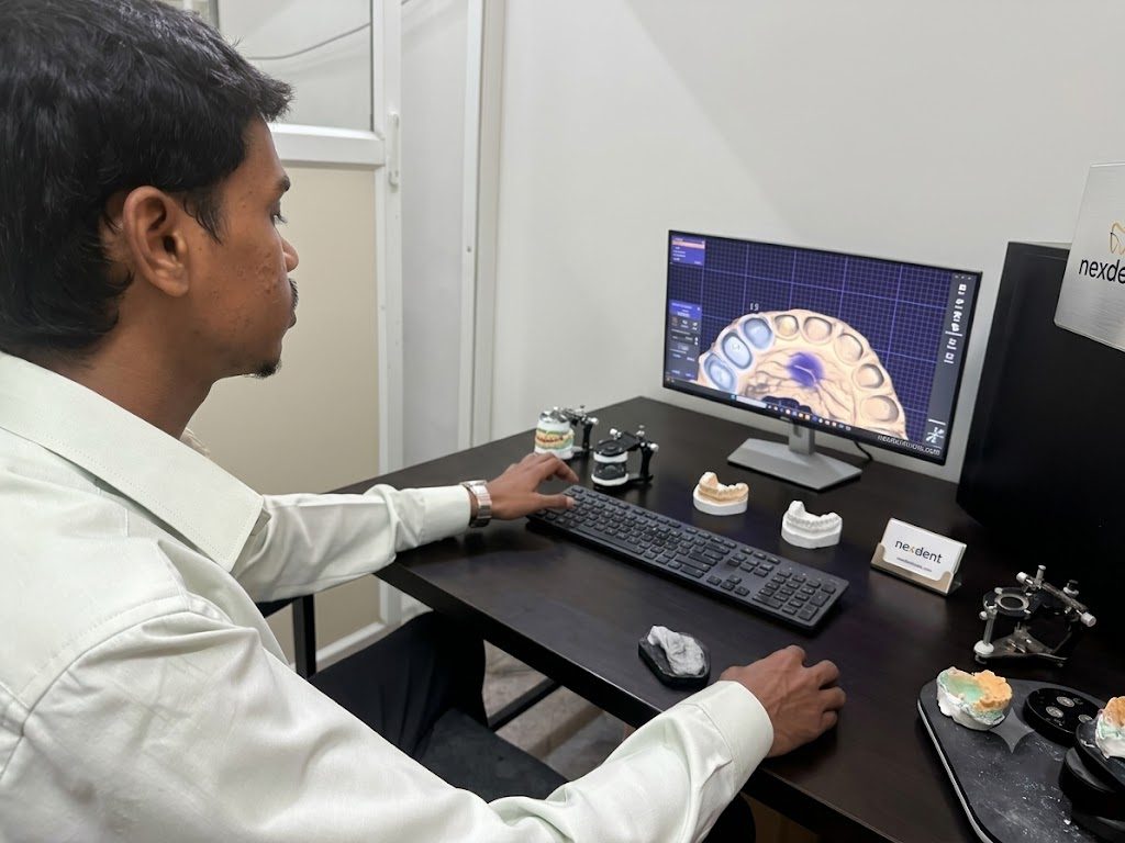 The design bench, with mounted models on articulators, the keyboard and the arch on the monitor